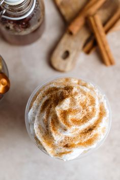 an overhead view of a cup of coffee with cinnamon on the top and spices around it