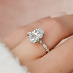 a close up of a person's hand with a diamond ring on their finger