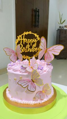 a pink birthday cake with gold butterflies on it and a happy birthday sign in the middle