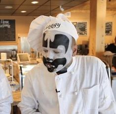 two chefs in white uniforms with black face paint on their faces and one wearing a chef's hat