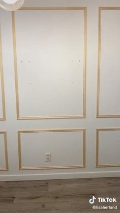 an empty room with white walls and gold trim on the wall, along with wood flooring