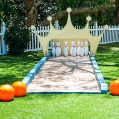 bowling balls are lined up in front of a white picket fence with a crown on top