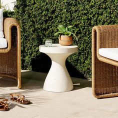 two wicker chairs sitting next to each other on top of a cement floor covered patio