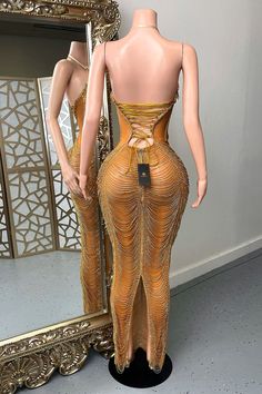 a mannequin is standing in front of a mirror and wearing a gold dress