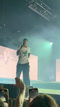 a man standing on top of a stage while holding up his cell phone in front of him