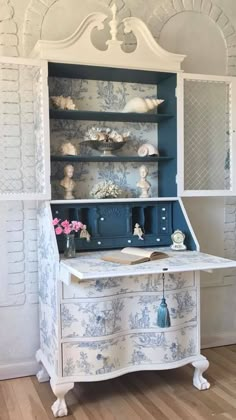 an old china cabinet with blue and white wallpaper