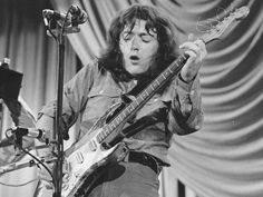 black and white photo of man playing guitar on stage