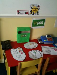 a red table topped with lots of paper plates and phone on top of it next to a green box