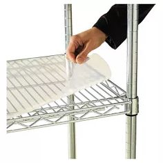 a person holding a piece of paper on top of a metal rack with wire shelves