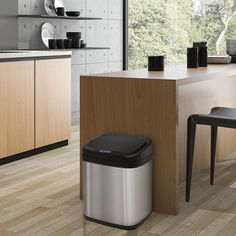 a modern kitchen with stainless steel trash can and wooden countertop, along with black chairs