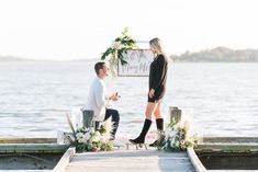 a man and woman standing on a dock with a sign that says it's my wedding