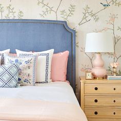 a blue headboard in a bedroom next to a dresser with drawers and a lamp