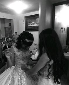 two women in wedding dresses are looking at something on the mirror while another woman is brushing her hair