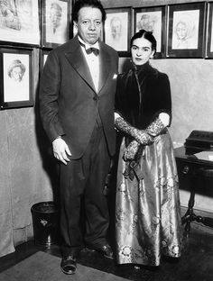 a man and woman standing next to each other in front of pictures on the wall