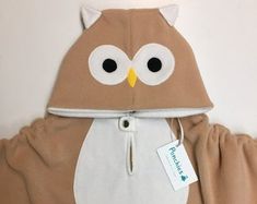 an owl hoodie is hanging on the wall next to a stuffed animal with a tag in it's ear