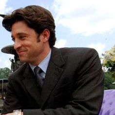 a man in a suit and tie sitting at a table with his hands folded out