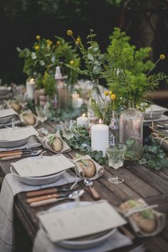 the table is set with place settings and candles for an outdoor dinner party or reception