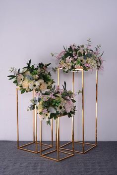 three gold plant stands with flowers on them