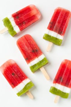 watermelon and kiwi popsicles are arranged on a white surface, ready to be eaten