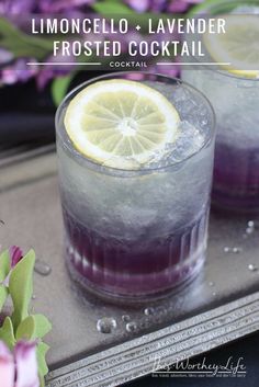 two glasses filled with lemon and lavender frosted cocktails on a tray next to flowers