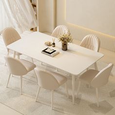 a white table with chairs and a book on it in the middle of a room