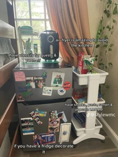 a refrigerator with magnets and pictures on it sitting in front of a window next to a plant