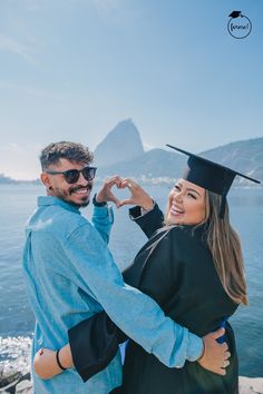 a man and woman in graduation gowns standing by the water