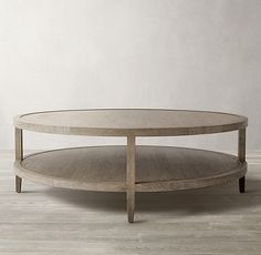 an oval coffee table with wooden legs and a glass top on a white wood floor