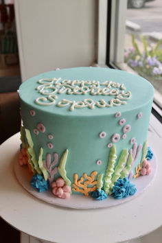 a birthday cake with blue frosting and seaweed on the bottom is sitting on a table