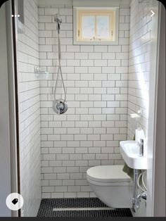 a white toilet sitting in a bathroom next to a sink and shower head mounted on a wall