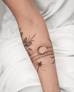 a woman's arm with flowers and a sun tattoo on the left side of her arm