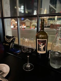 a bottle of wine sitting on top of a table next to a glass filled with water