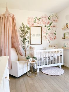 a baby's room with pink flowers on the wall and a white crib