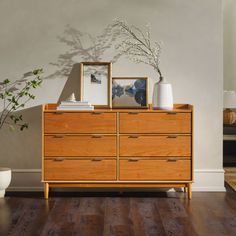 a wooden dresser sitting on top of a hard wood floor next to a potted plant