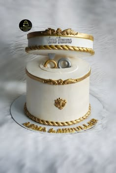 there is a wedding cake that has two rings on the top and gold trimmings