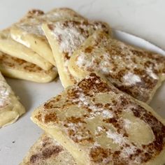 some food is on a white plate and has powdered sugar on it, as well as other foods