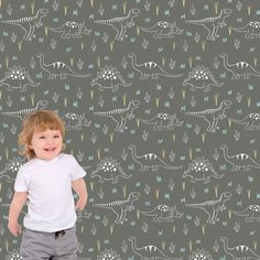 a little boy standing in front of a wallpaper with dinosaurs and plants on it