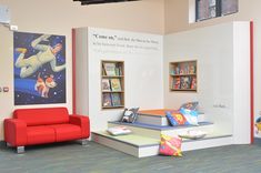 a red couch sitting next to a book shelf filled with books