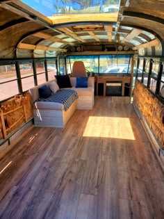 the inside of a bus with wood flooring and couches in front of it