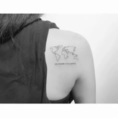 a woman's shoulder with a small world map tattoo on the back of her arm