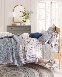 a bed with blue and white comforters on top of it next to a dresser