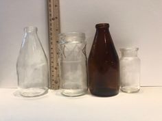 three glass bottles are lined up next to a ruler