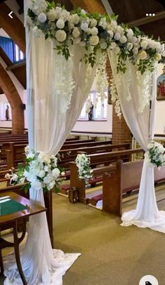 an aisle decorated with white flowers and greenery