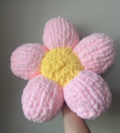 a hand holding a pink and yellow knitted flower