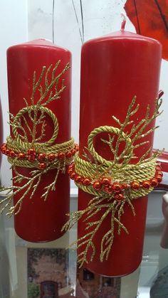 two red candles decorated with gold thread and twine, sitting next to each other