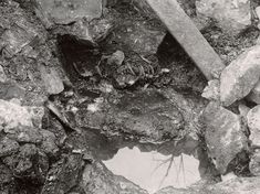 an old photo of rocks and rubble with water in the hole on the ground next to it