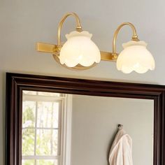 a bathroom mirror with two lights on it and a towel hanging in front of the mirror