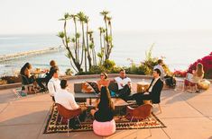 a group of people sitting on top of a patio next to the ocean