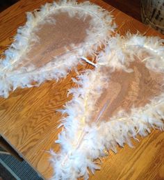 two pieces of white feathers sitting on top of a wooden table