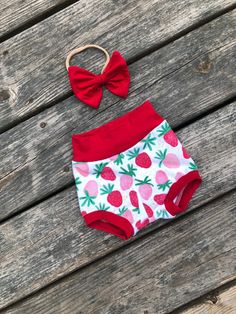 Strawberry themed bummie shorts. Made with soft cotton spandex knit with red and pink strawberries. Red waist and cuffs. Matching red bow on nylon headband. Bummies are made to be a little smaller than regular shorts and fit snug. If you don't want them snug order a size up. Matching white bodysuit with ONE in red. Cute Short Diaper Cover For Summer, Cute Summer Short Diaper Cover, Cute Short Summer Diaper Cover, Pink Strawberry Print Bottoms For Summer, Fun Red Summer Bottoms, Cute Summer Diaper Cover For First Birthday, Playful Bottoms For First Birthday In Summer, Playful Summer Bottoms For First Birthday, Cute Short Red Bottoms